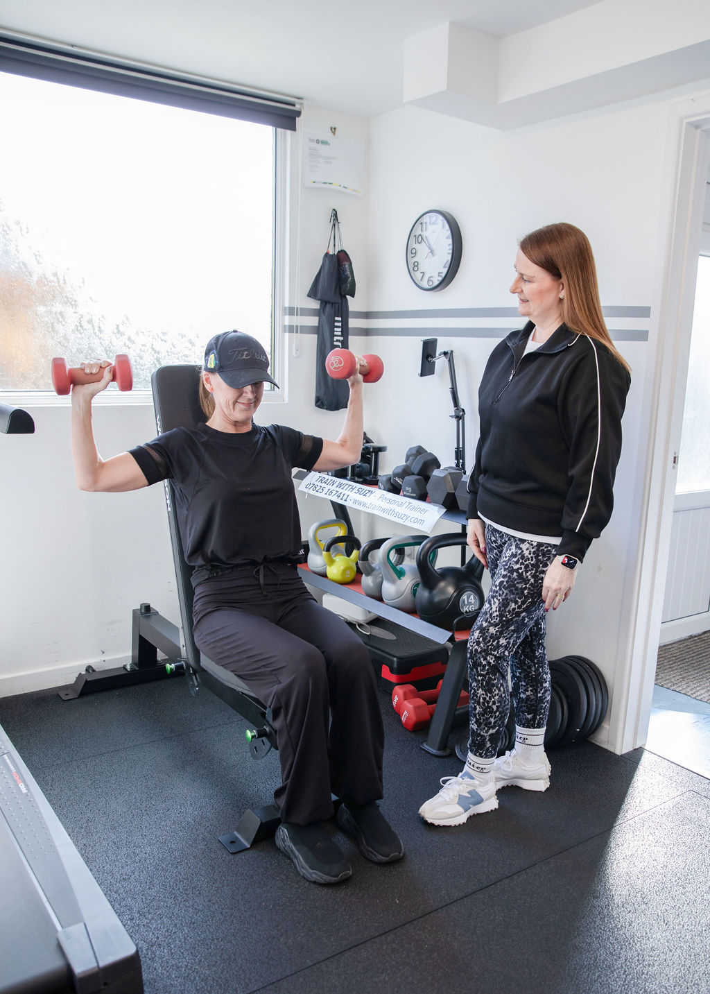 Suzy coaching a client through a dumbbell shoulder press in her private Sheffield gym